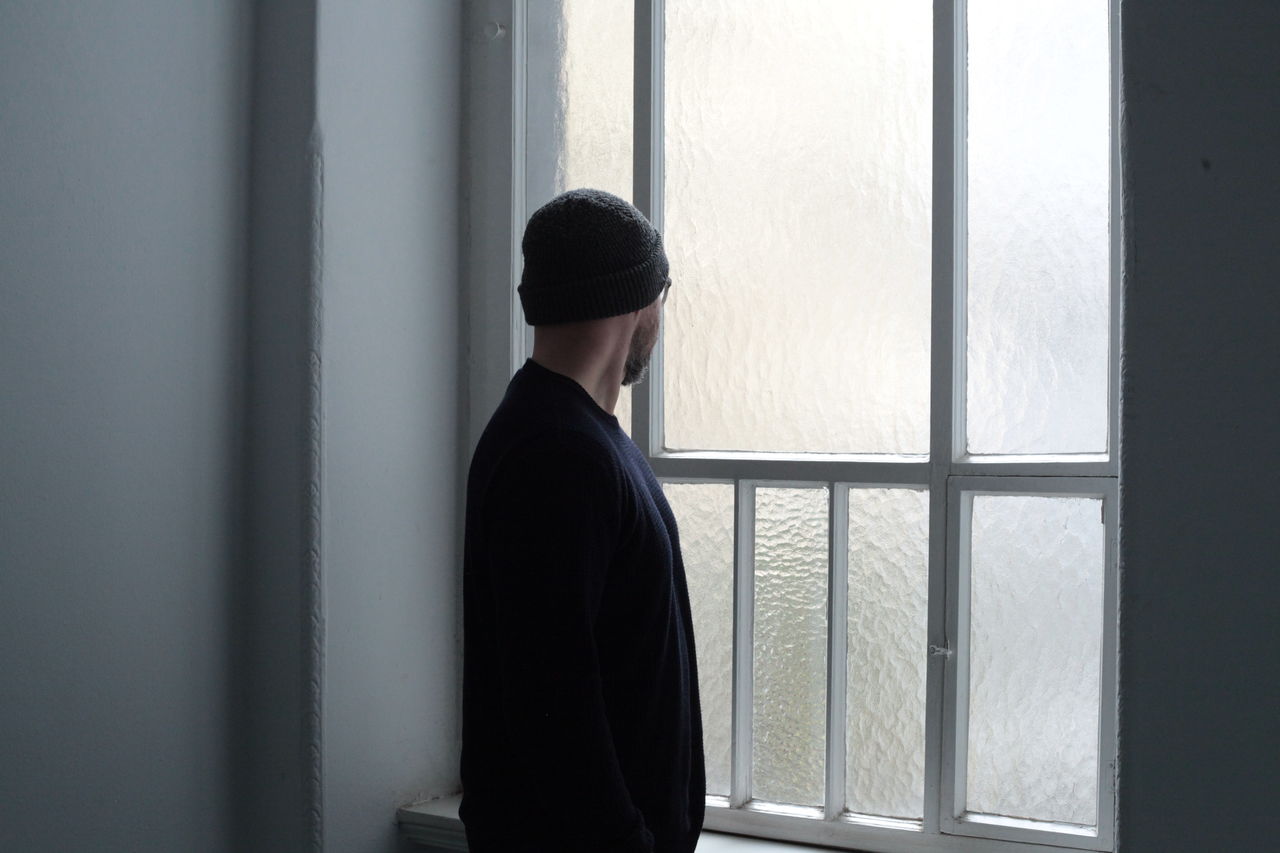 Man looking through window at home