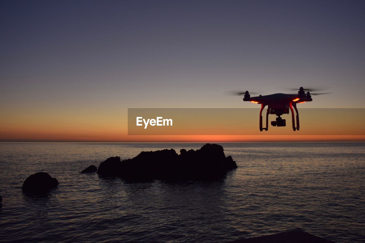 Drone flying over sea during sunset