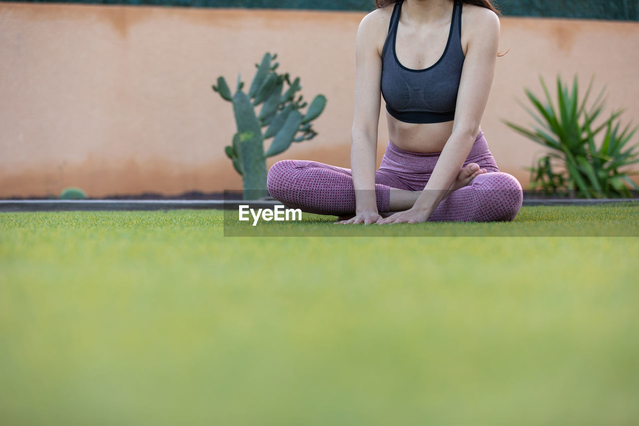 sports, exercising, one person, lifestyles, women, adult, sports clothing, grass, wellbeing, green, leisure activity, plant, yoga, clothing, relaxation, young adult, nature, selective focus, female, physical fitness, activity, copy space, day, exercise mat, athlete, practicing, zen-like, vitality, front view, outdoors, sports training, full length, person, casual clothing, surface level, concentration