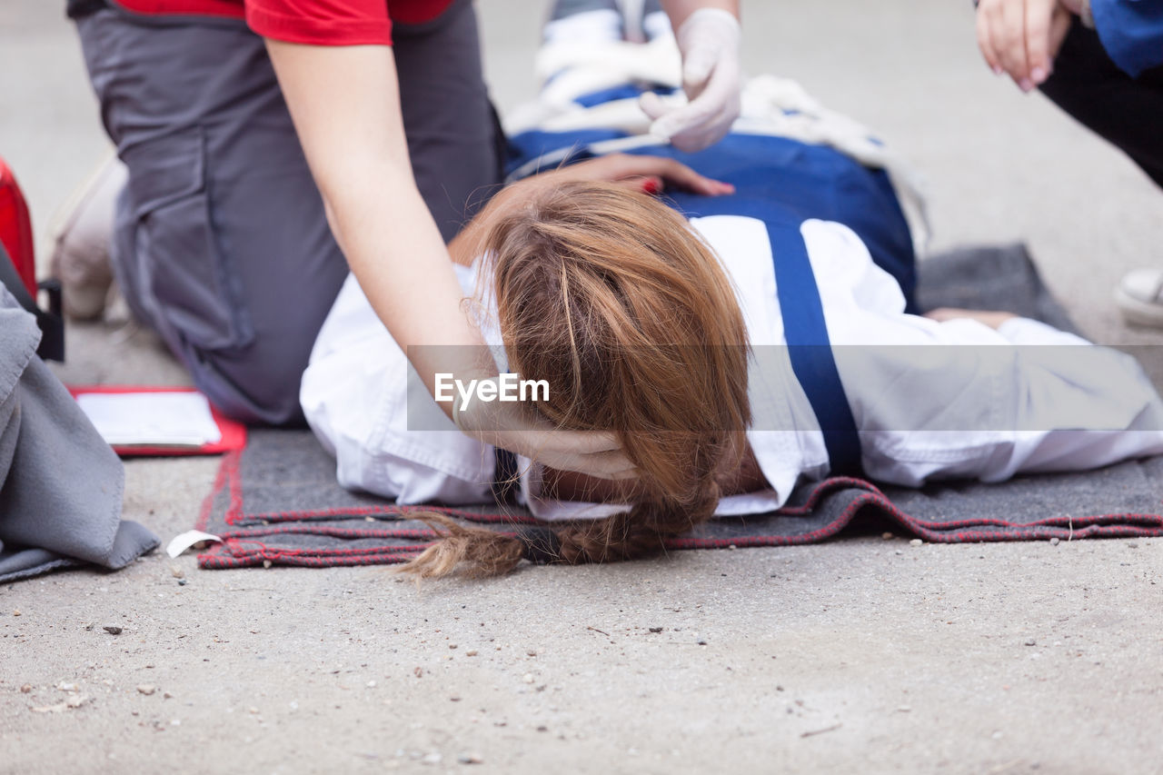 Low section of paramedic treating female patient on field