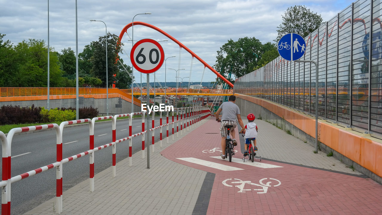 Rear view of father and son riding bicycle in city