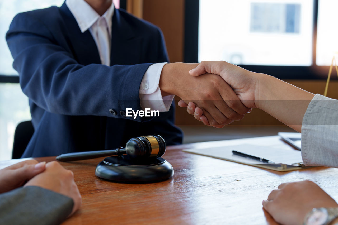 midsection of lawyer and client shaking hands