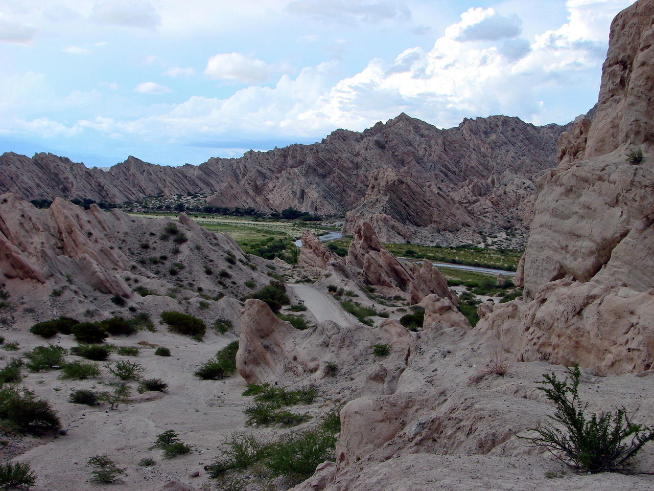 Scenic view of road travelling through mountains against cloudy sky