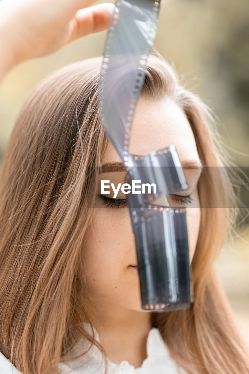 Close-up of young woman holding film reel outdoors