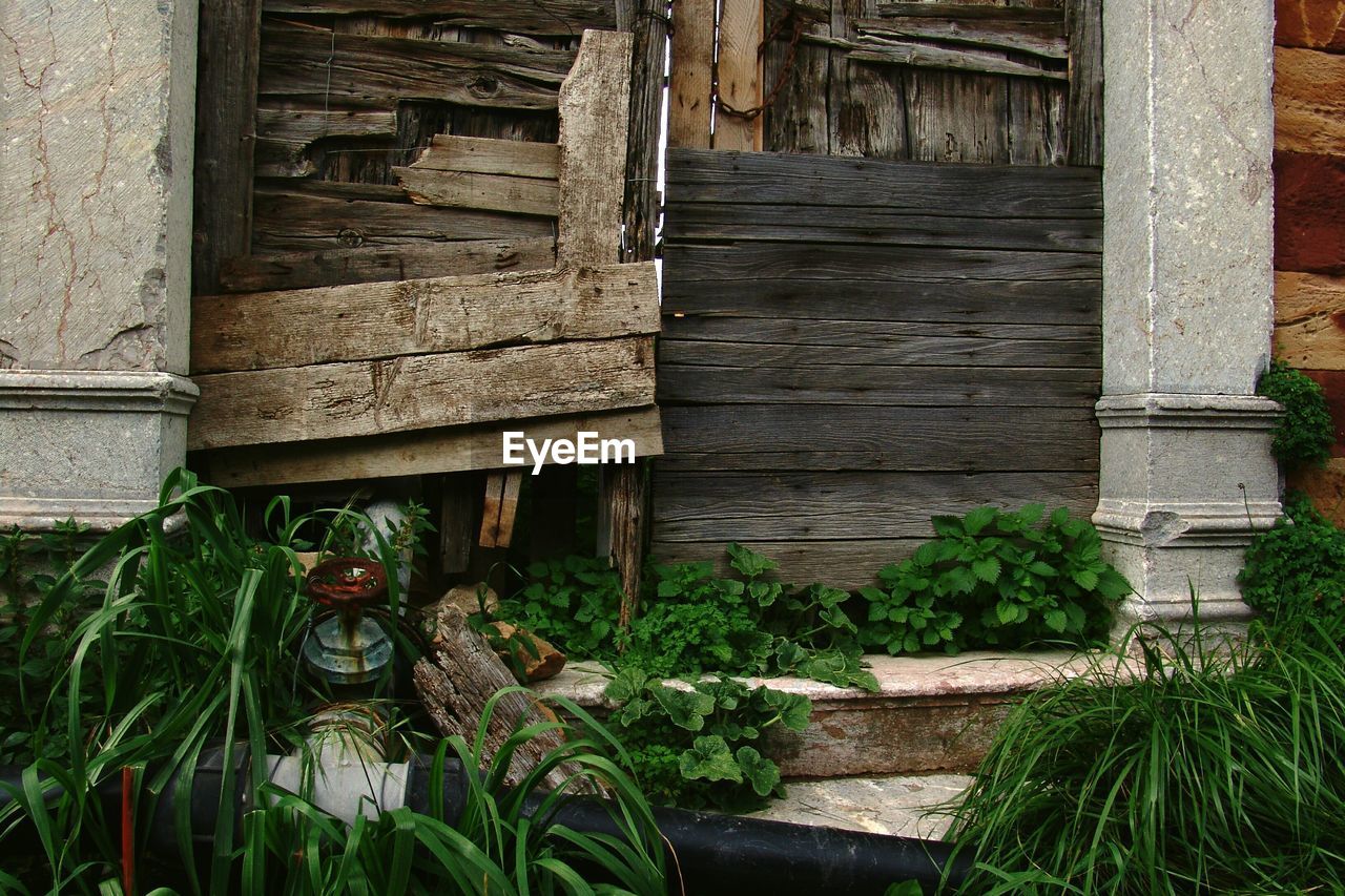 Pipeline amidst grass against old wooden house