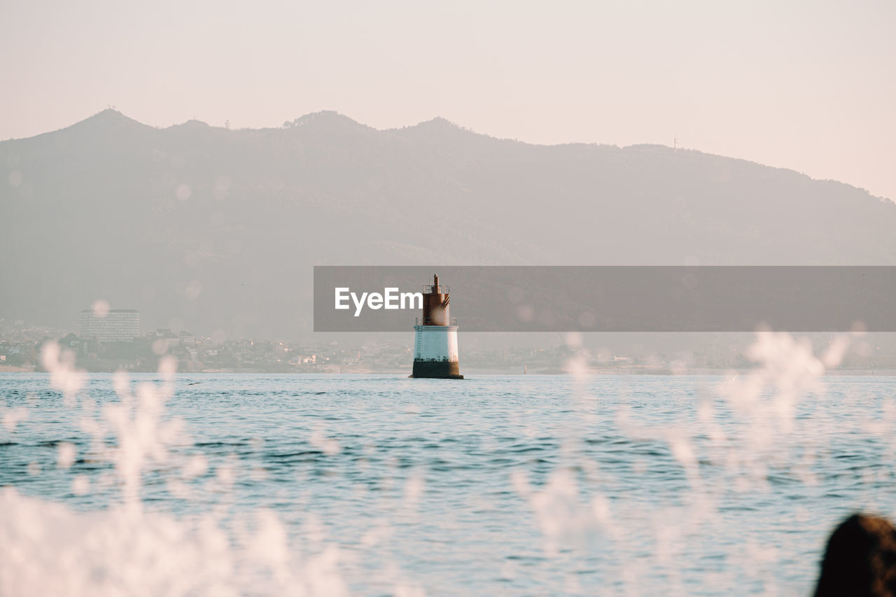 Rear view of woman in sea against mountain range