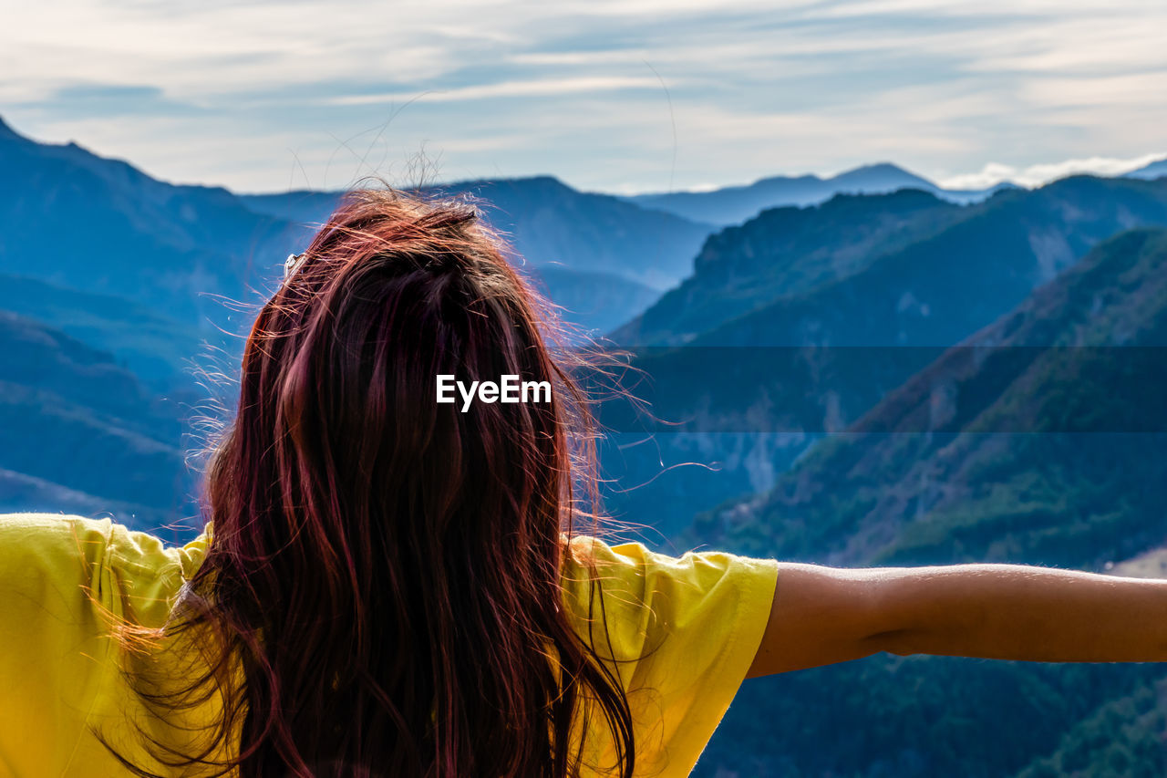 REAR VIEW OF WOMAN WITH UMBRELLA AGAINST MOUNTAIN RANGE