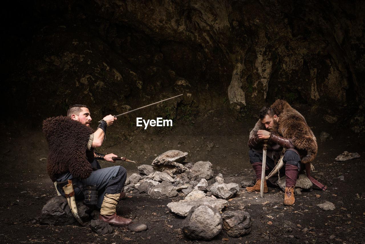 Warriors with weapon sitting on rock in forest