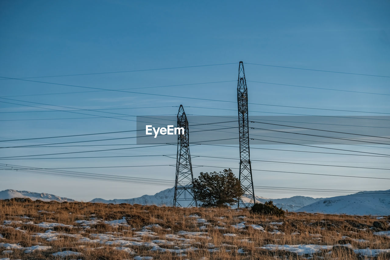 Electricity pylon on land against sky during winter