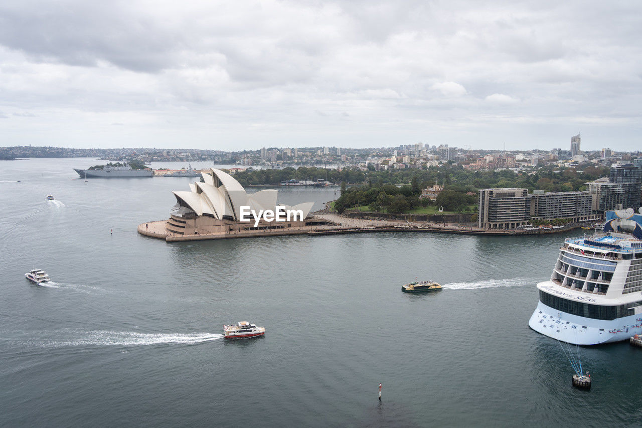 water, transportation, architecture, nautical vessel, vehicle, ship, city, mode of transportation, built structure, travel destinations, building exterior, travel, passenger ship, sea, sky, cloud, boat, harbor, craft, nature, cityscape, building, ferry, tourism, watercraft, high angle view, no people, bay, landscape, coast, day, outdoors, cruise, vacation, holiday, trip, urban skyline, bridge, environment, aerial view, overcast, scenics - nature