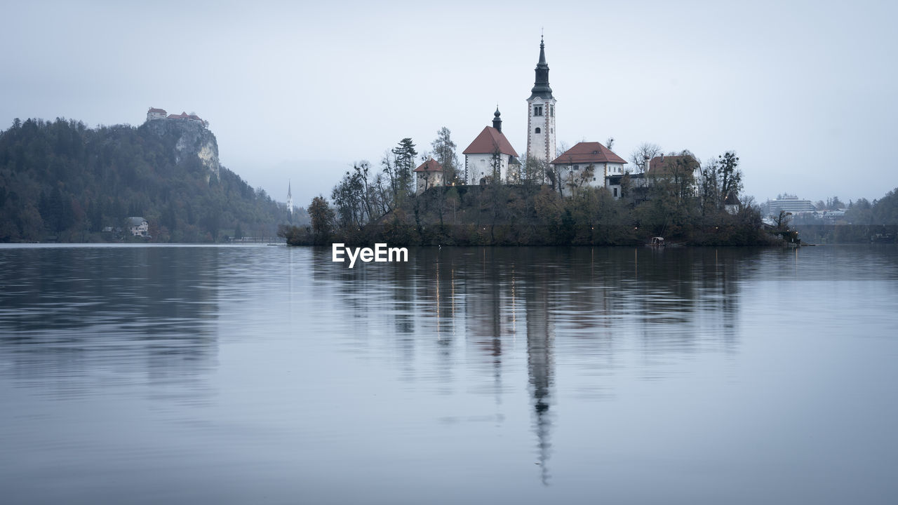 reflection, water, architecture, sky, travel destinations, built structure, nature, religion, building, building exterior, place of worship, no people, lake, travel, tree, scenics - nature, tourism, spirituality, tranquility, landscape, history, belief, plant, outdoors, morning, day, bay, beauty in nature, environment, the past, land, mountain, tranquil scene, tower, city