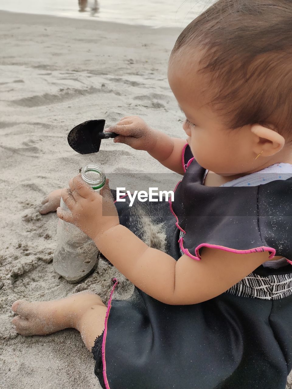 Baby girl playing sandbeach with plastic bottles