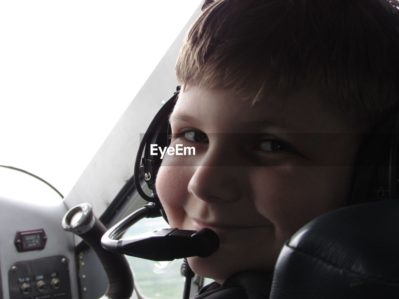 Portrait of boy with microphone sitting in airplane cockpit