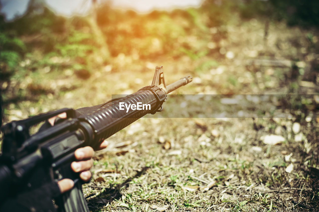 Cropped image of military office aiming weapon on field