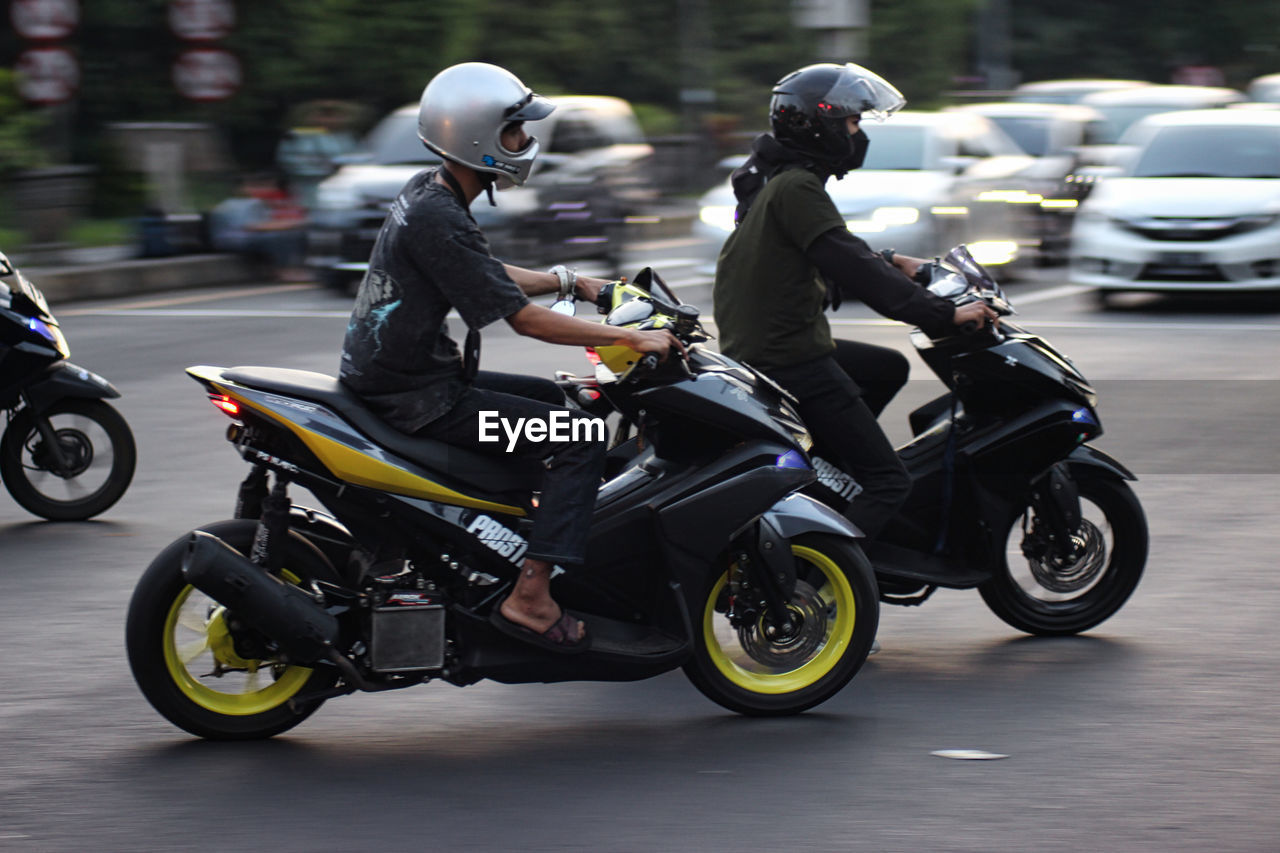 PEOPLE RIDING SCOOTER ON ROAD