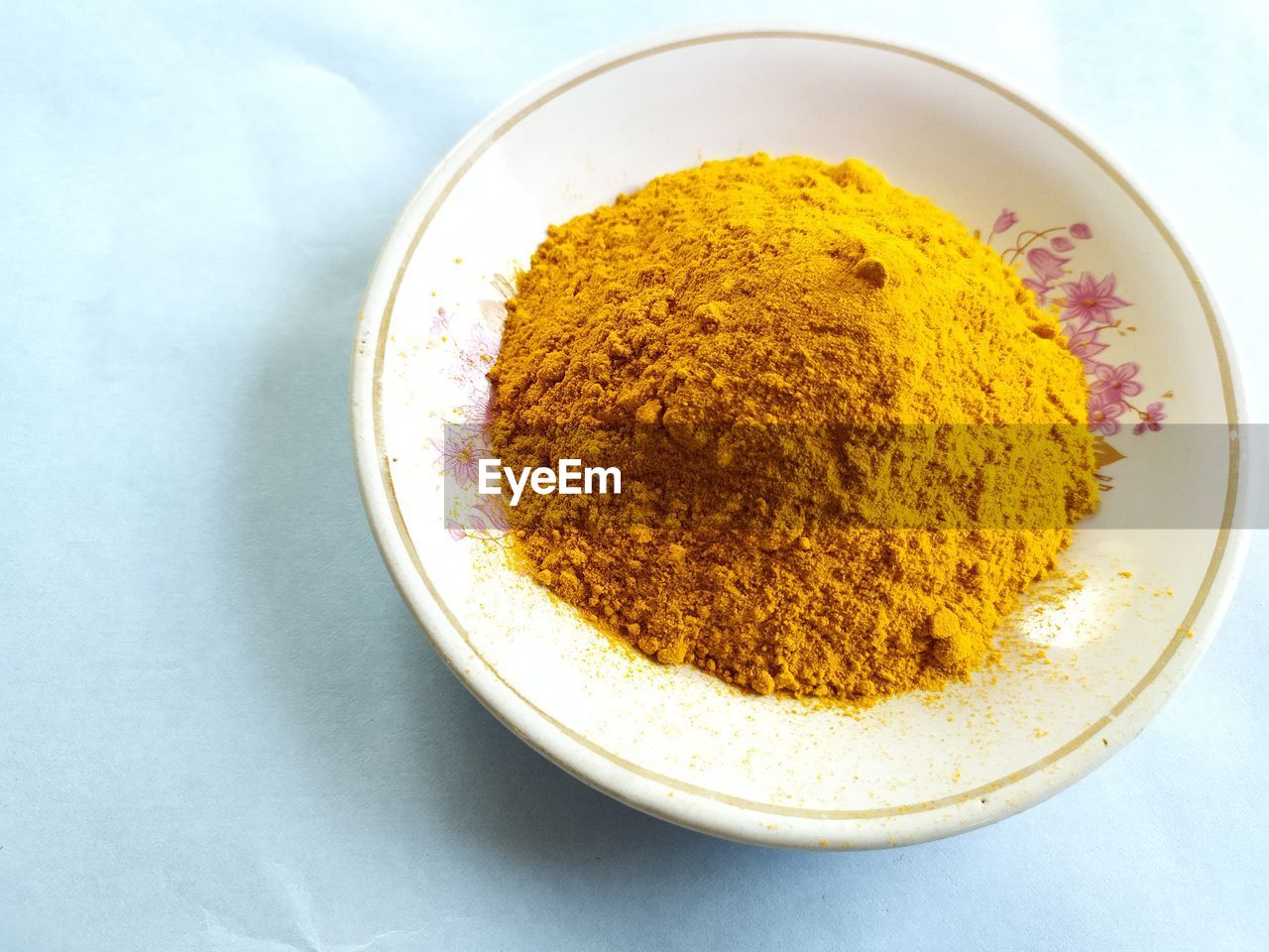 Turmeric powder on plate, an essential ingredient for cooking, white background.