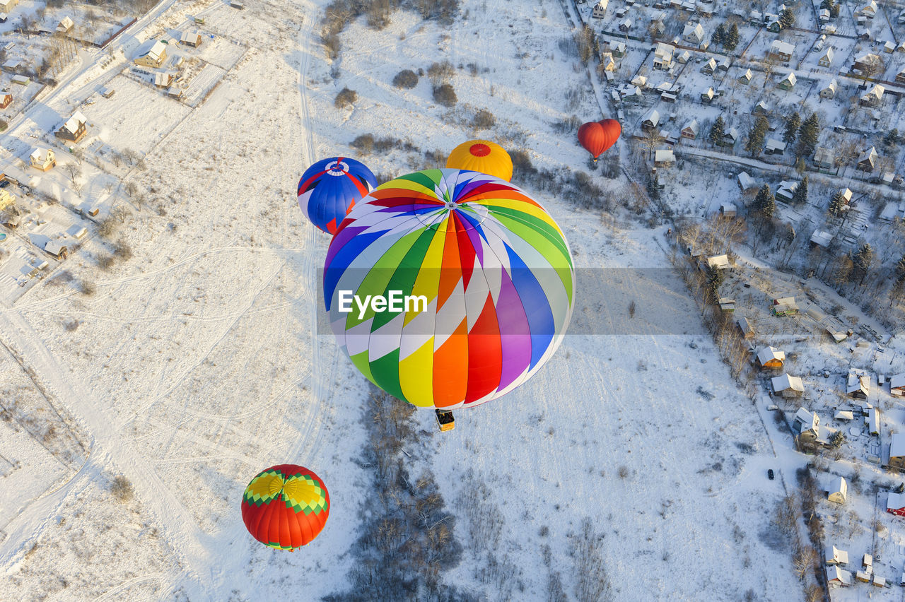High angle view of hot air balloons flying over snow covered land