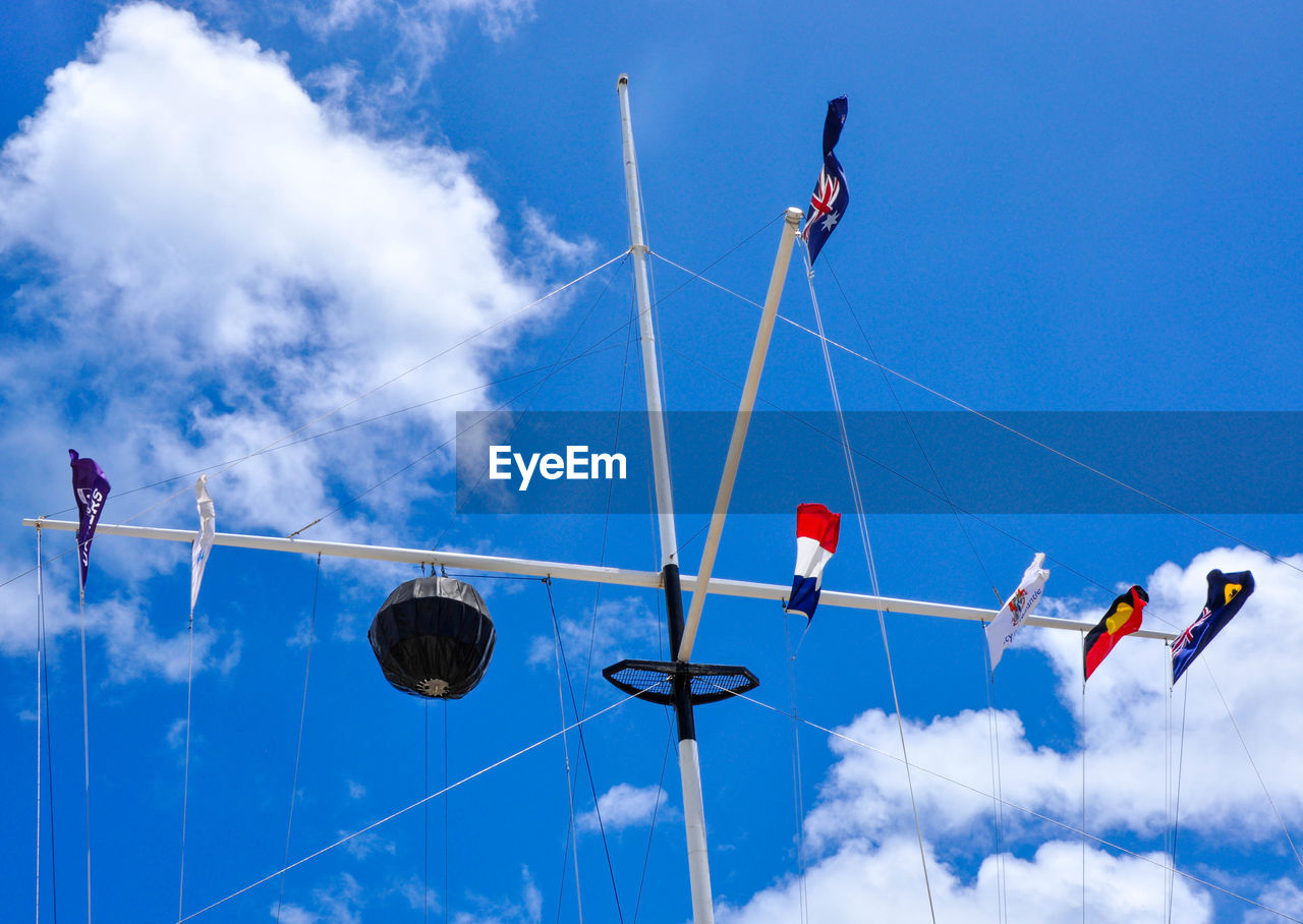 LOW ANGLE VIEW OF MEN HANGING AGAINST SKY