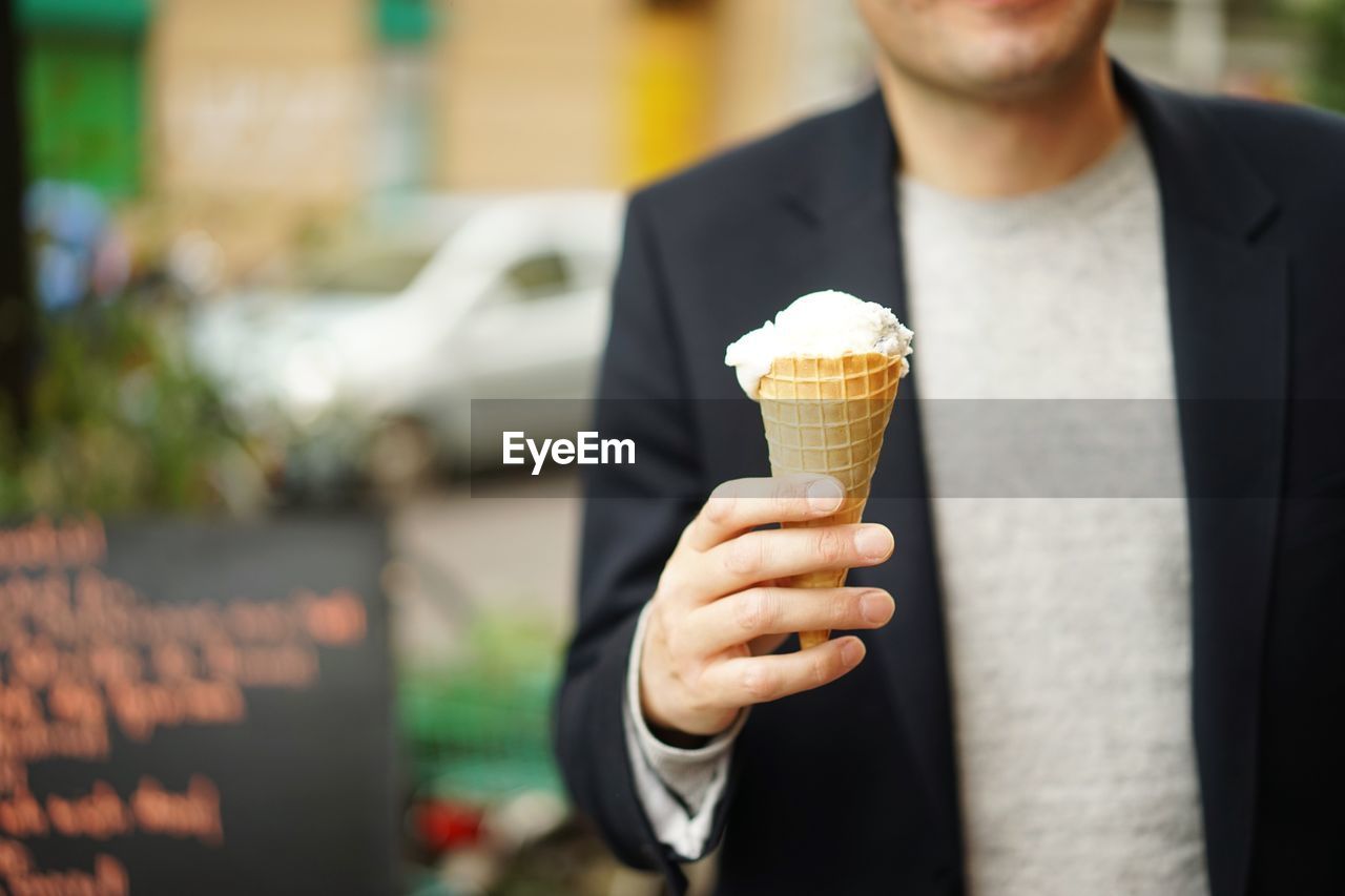Midsection of man holding ice cream on street