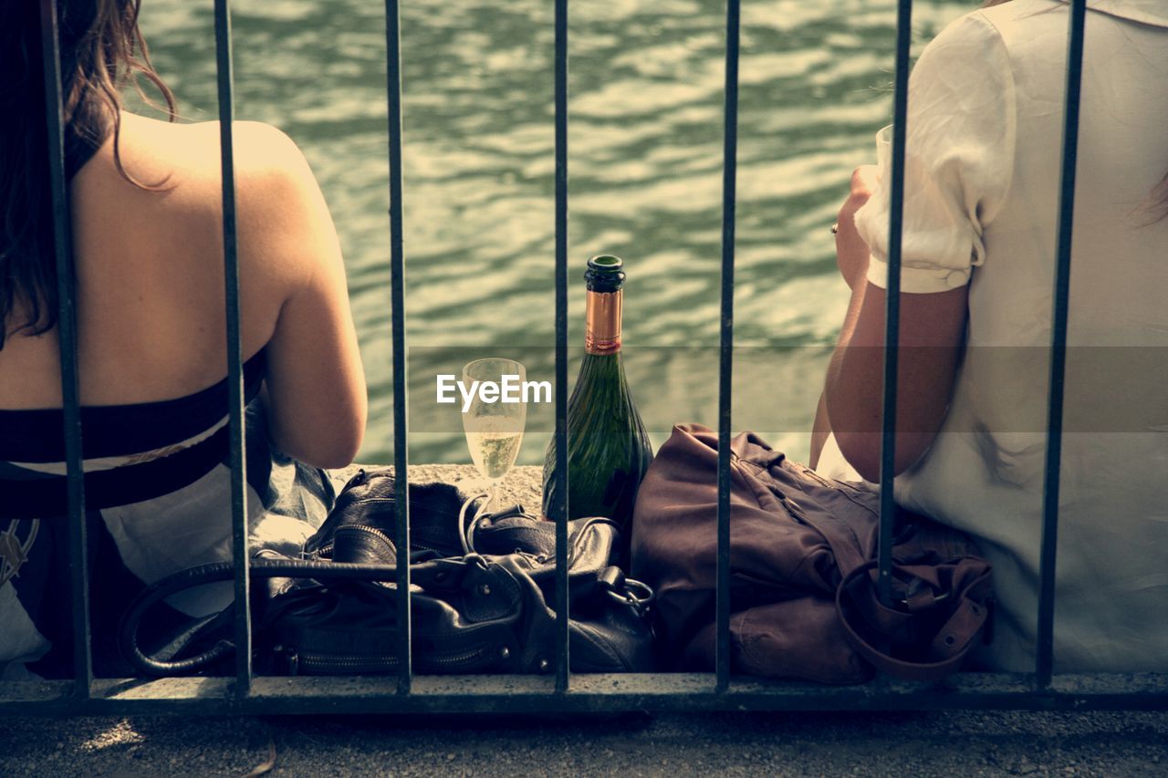 Rear view of couple with wine against rippled water