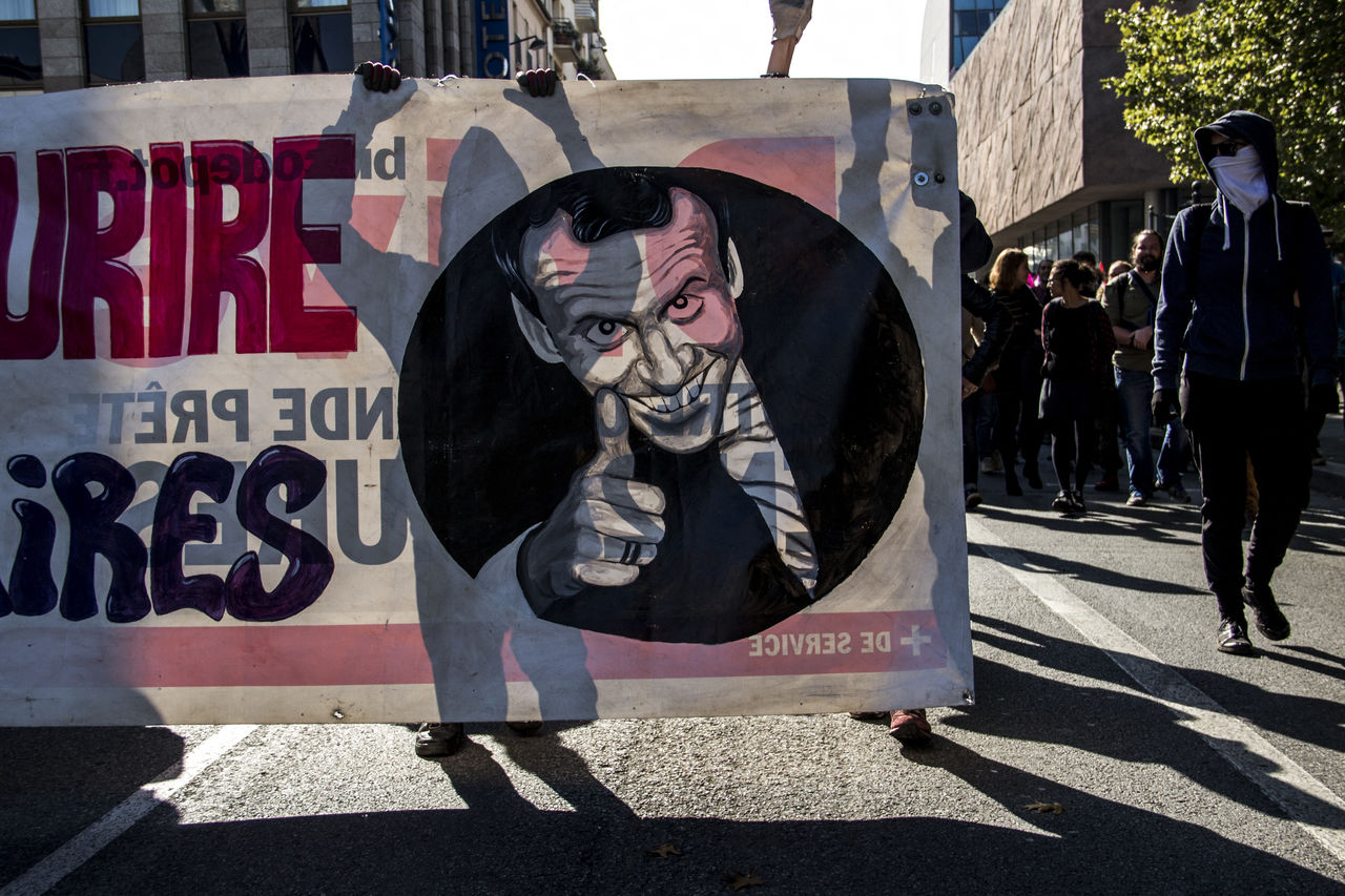 street, city, architecture, road, day, protest, sunlight, person, text, full length, shadow, adult, men, sign, outdoors, clothing, group of people, graffiti, communication, art