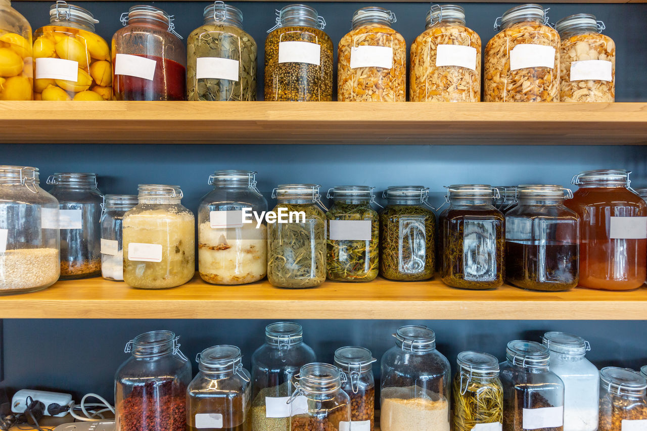 Jars of various kinds of preserved food, herbs, spices, and fruits on shelves