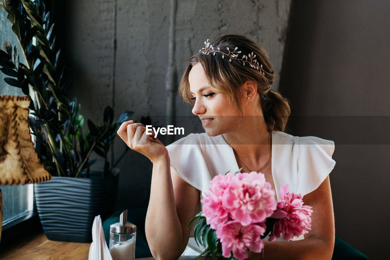 YOUNG WOMAN SITTING ON TABLE AT SIDEWALK CAFE