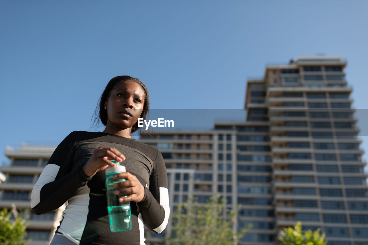 Black runner opening bottle of water