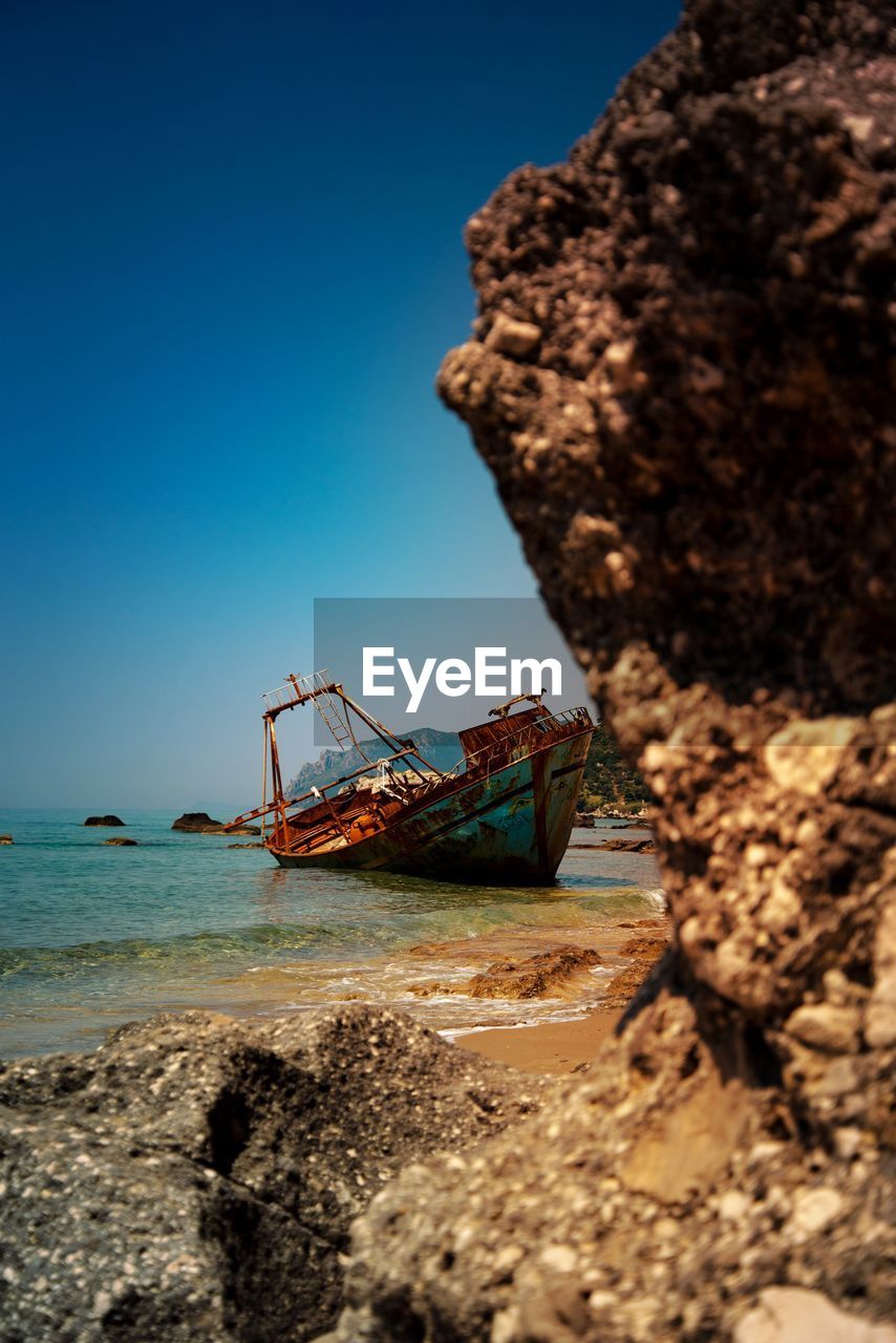 ABANDONED BOAT ON SHORE AGAINST CLEAR SKY