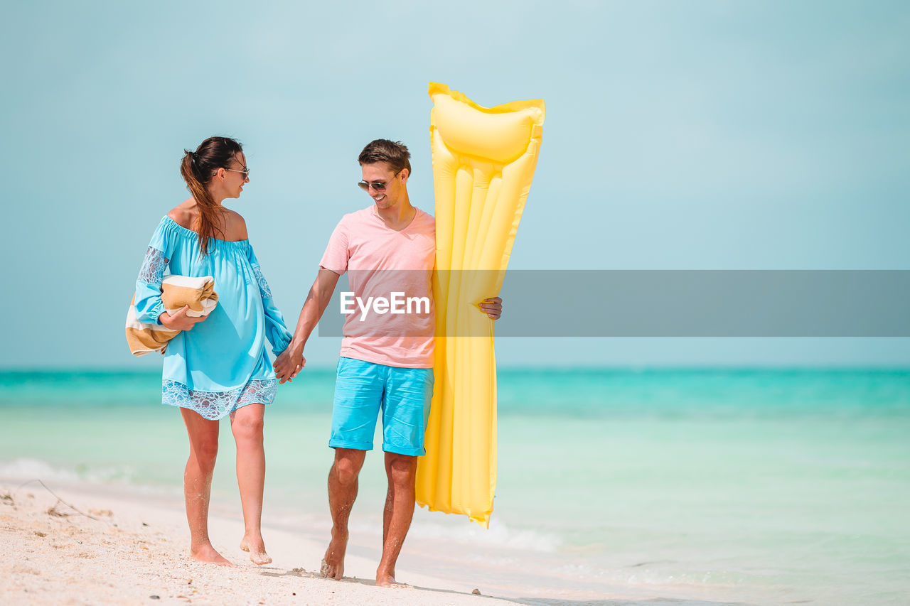 Couple walking on beach against sky