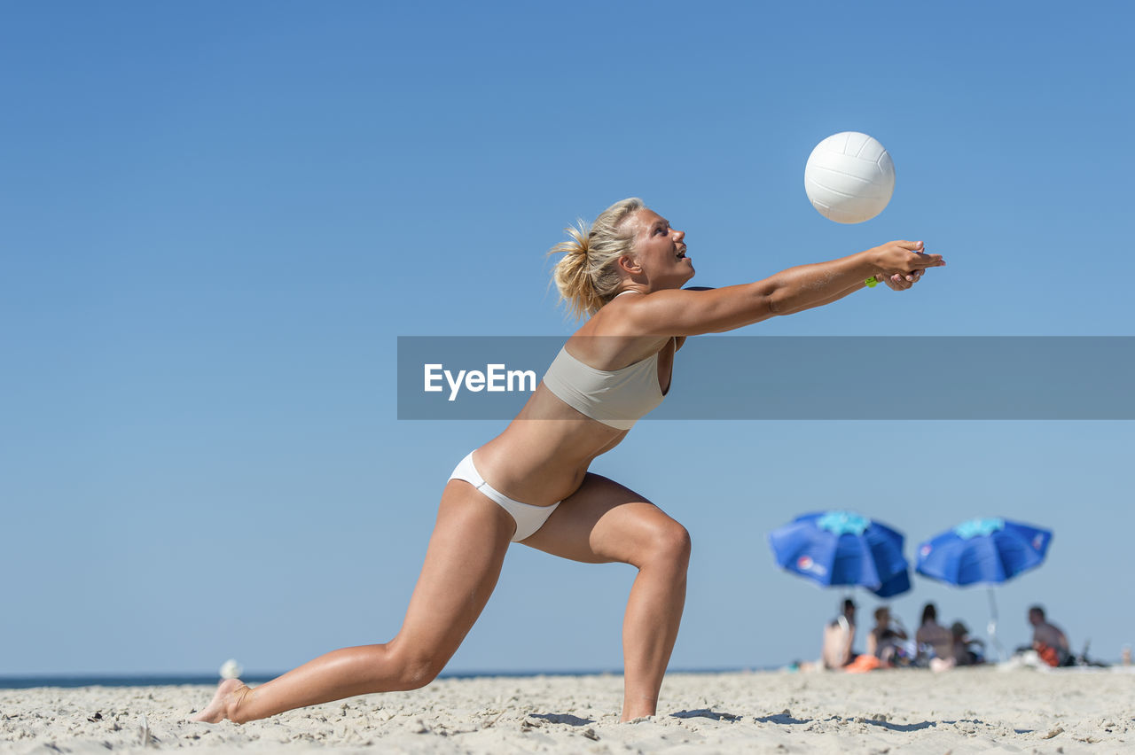 Full length of woman on beach against clear blue sky