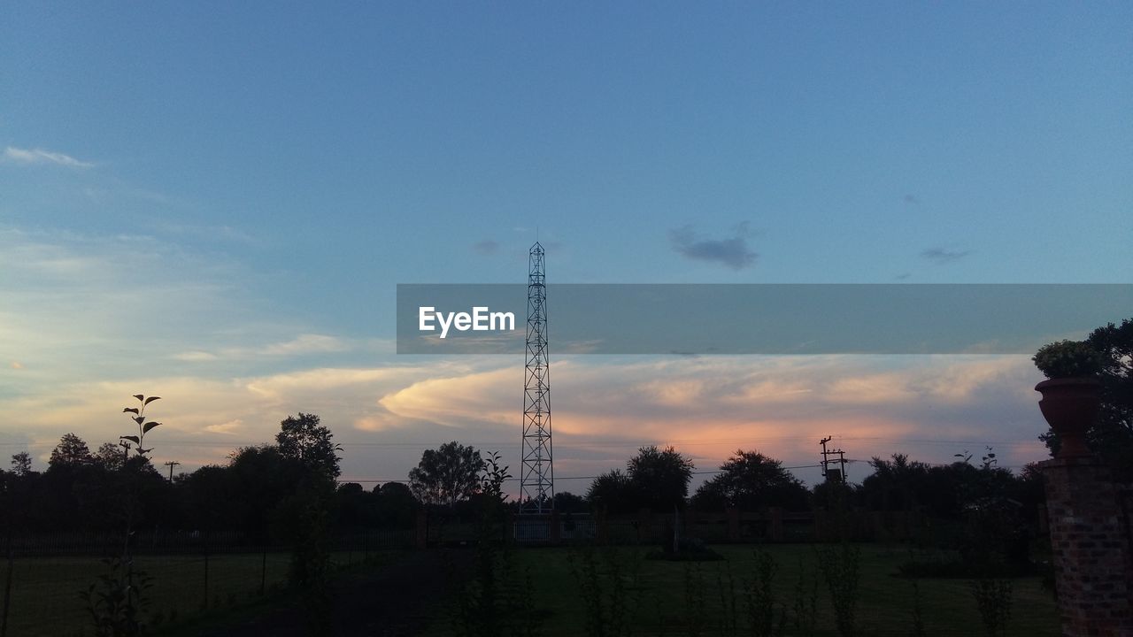 Communication tower on field against sky during sunset
