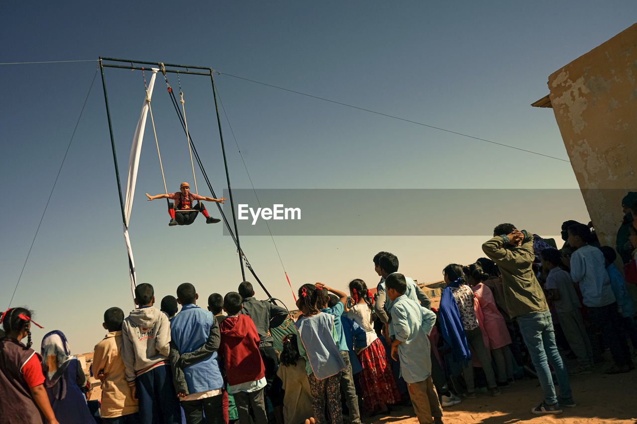 PEOPLE STANDING IN TRADITIONAL WINDMILL AGAINST SKY