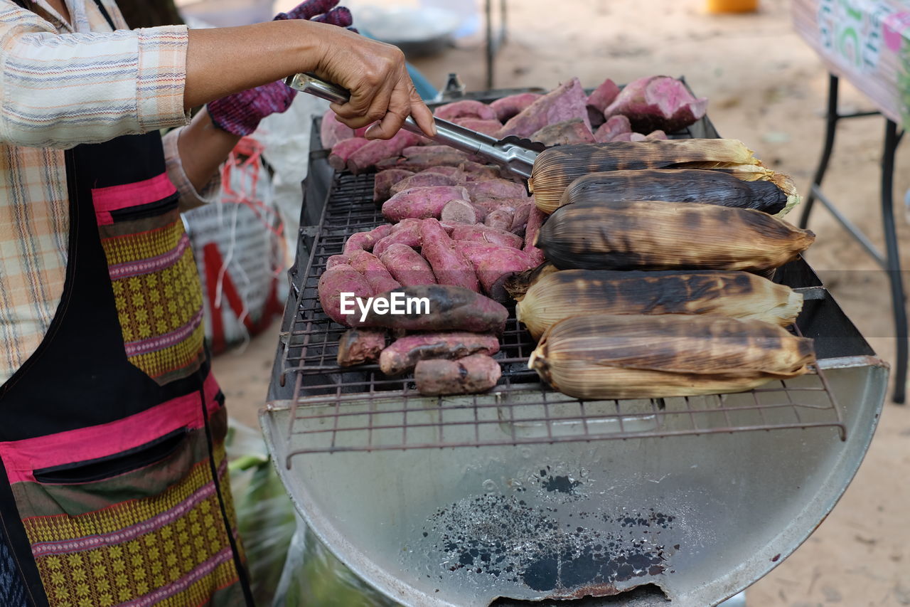 Midsection of man preparing food on barbecue grill