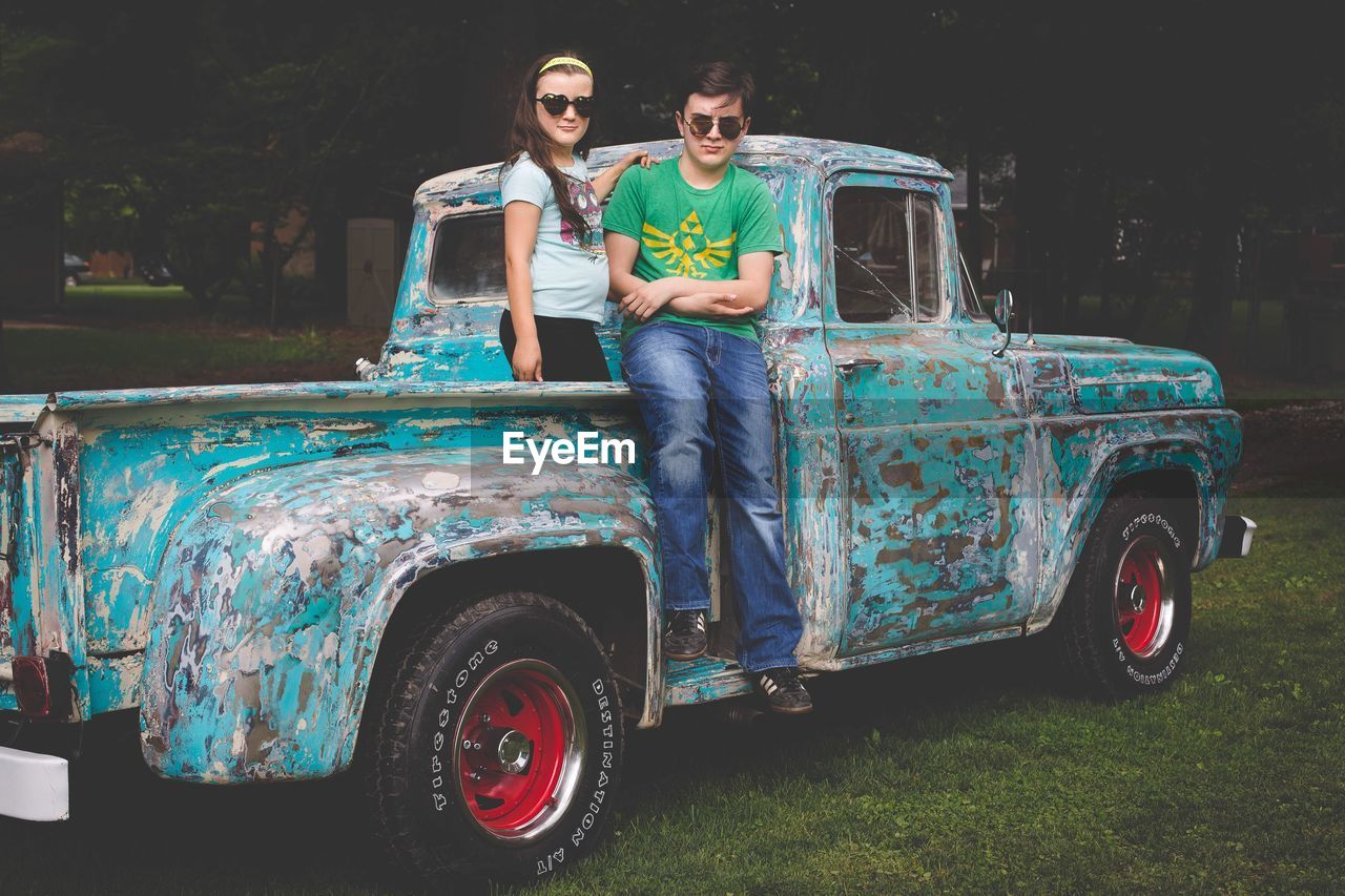 Siblings on rusty pick-up truck