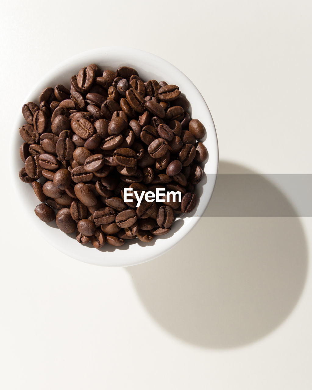 Close-up of coffee beans in bowl against white background