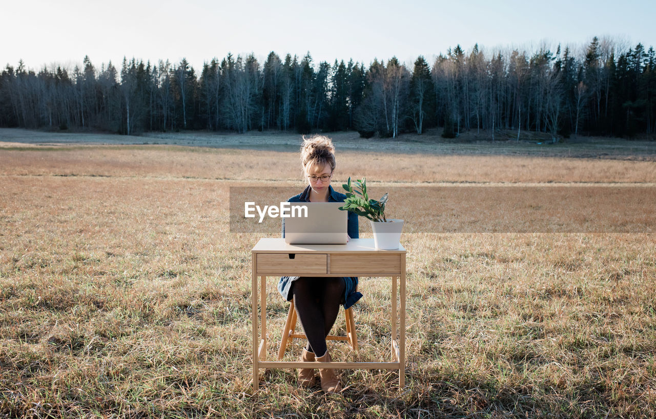 Woman flexible working on a desk and laptop outside in a field