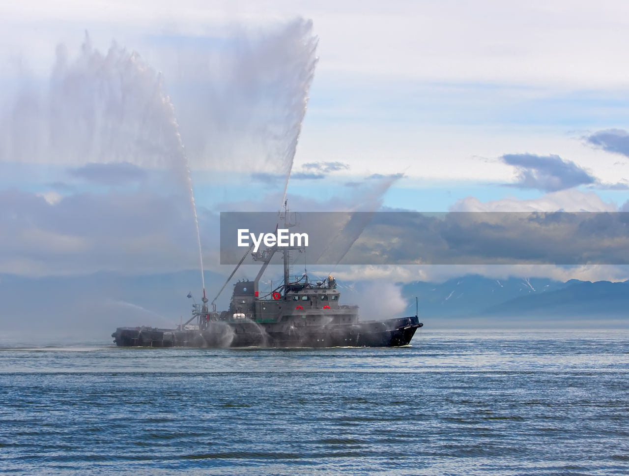 The floating tug boat is spraying jets of water