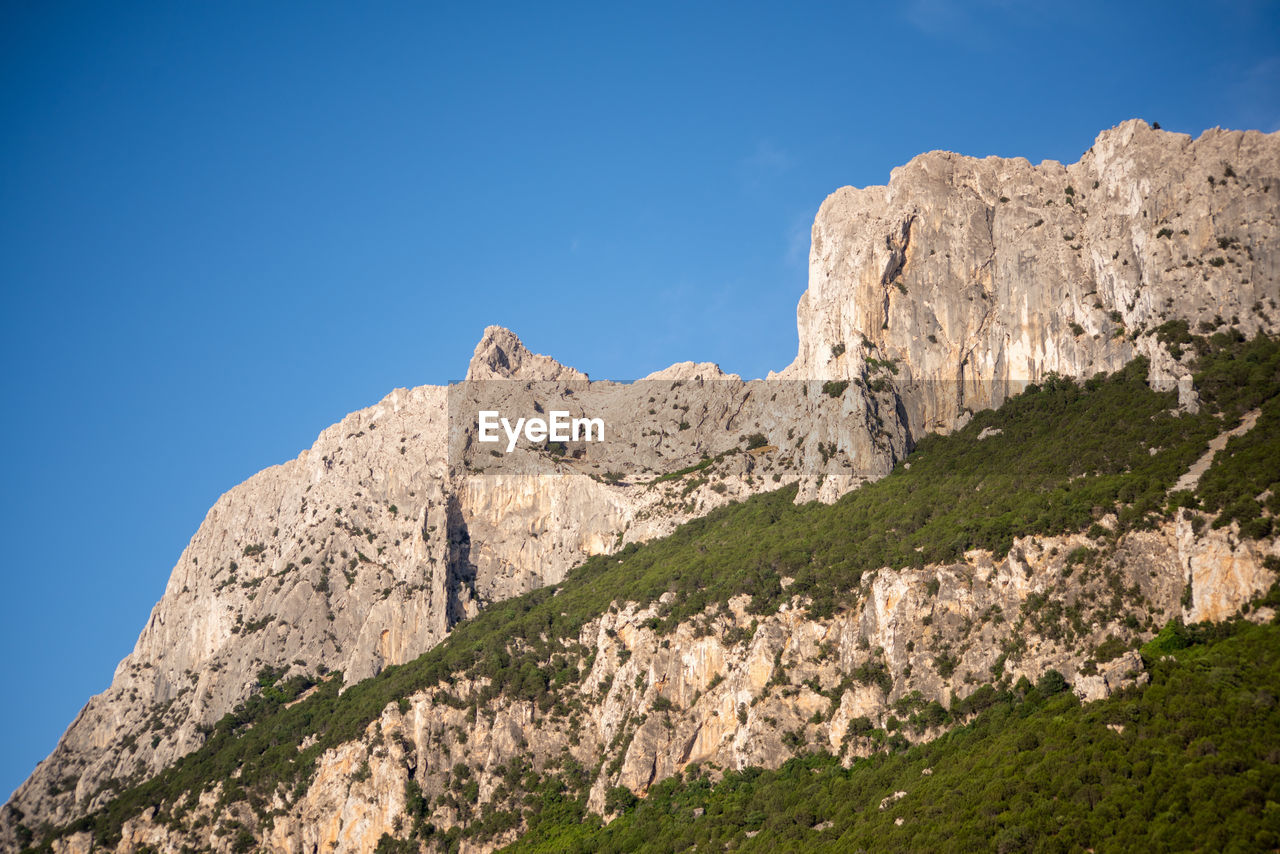 Low angle view of rock formation against clear blue sky