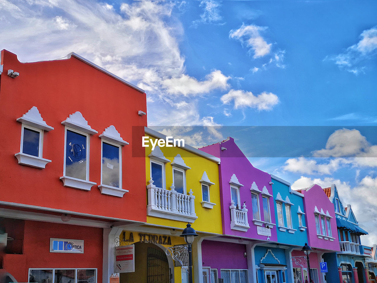 LOW ANGLE VIEW OF MULTI COLORED HOUSES AGAINST SKY