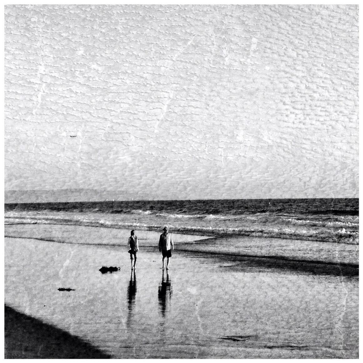 Couple standing on beach against sky