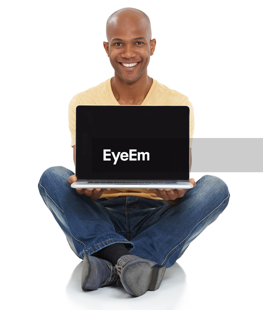 sitting, computer, smiling, laptop, technology, wireless technology, portrait, adult, communication, cut out, happiness, person, internet, computer network, one person, looking at camera, using laptop, casual clothing, white background, indoors, cheerful, studio shot, emotion, young adult, business, e-mail, front view, relaxation, men, copy space, jeans, clothing, smile, positive emotion, finger, shaved head, full length, portability, teeth, using computer, computer equipment, business finance and industry, human face, occupation, working