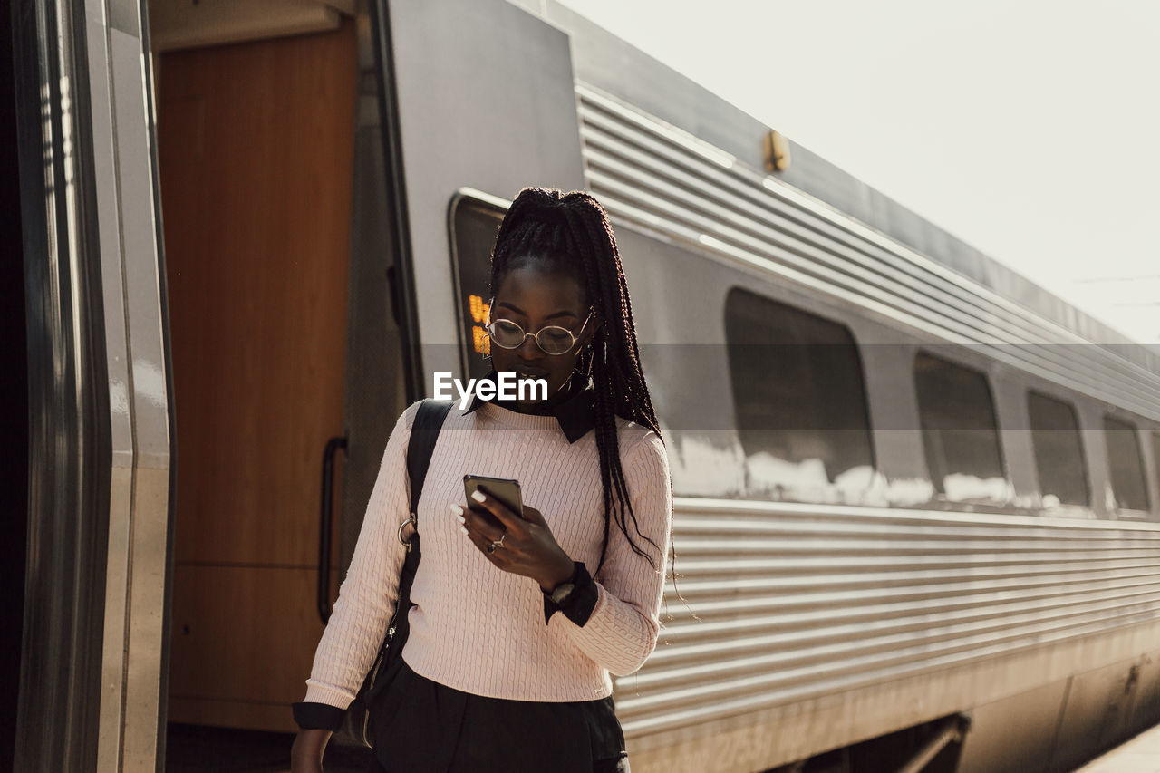 Young woman using phone at train station platform