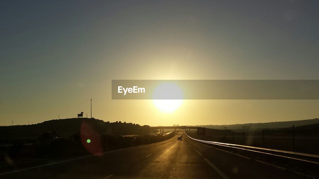 ROAD PASSING THROUGH EMPTY ROAD AT SUNSET