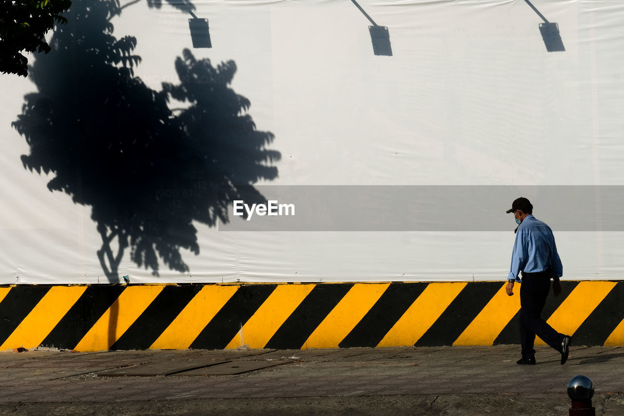 Side view of man standing on footpath