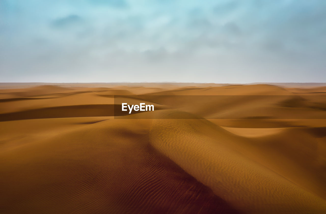 Sand dunes in desert against sky