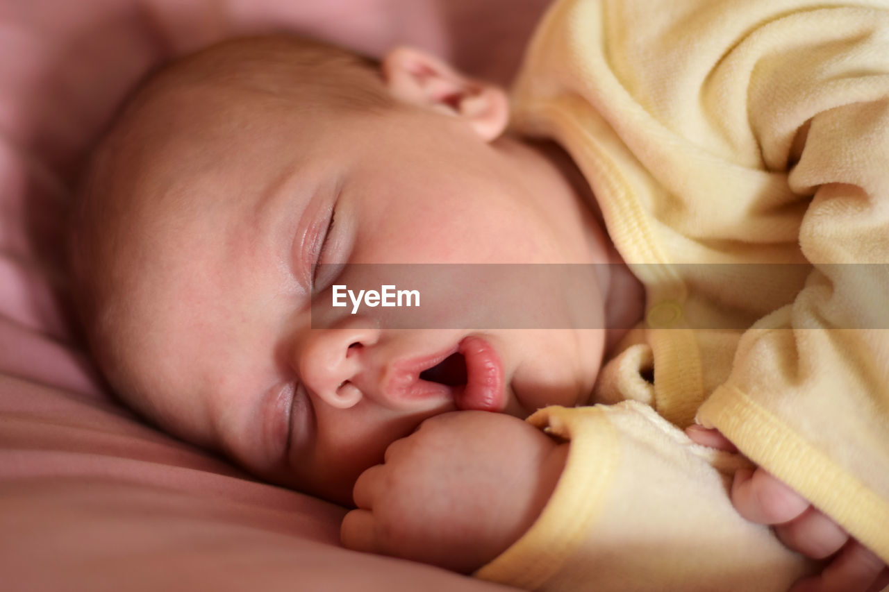 Newborn baby sleep with opened mouth. one, two week age. infant girl sleeping, lying on purple bed