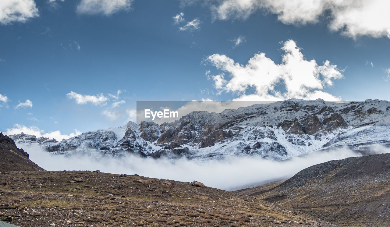 Scenic view of snowcapped mountains against cloudy sky