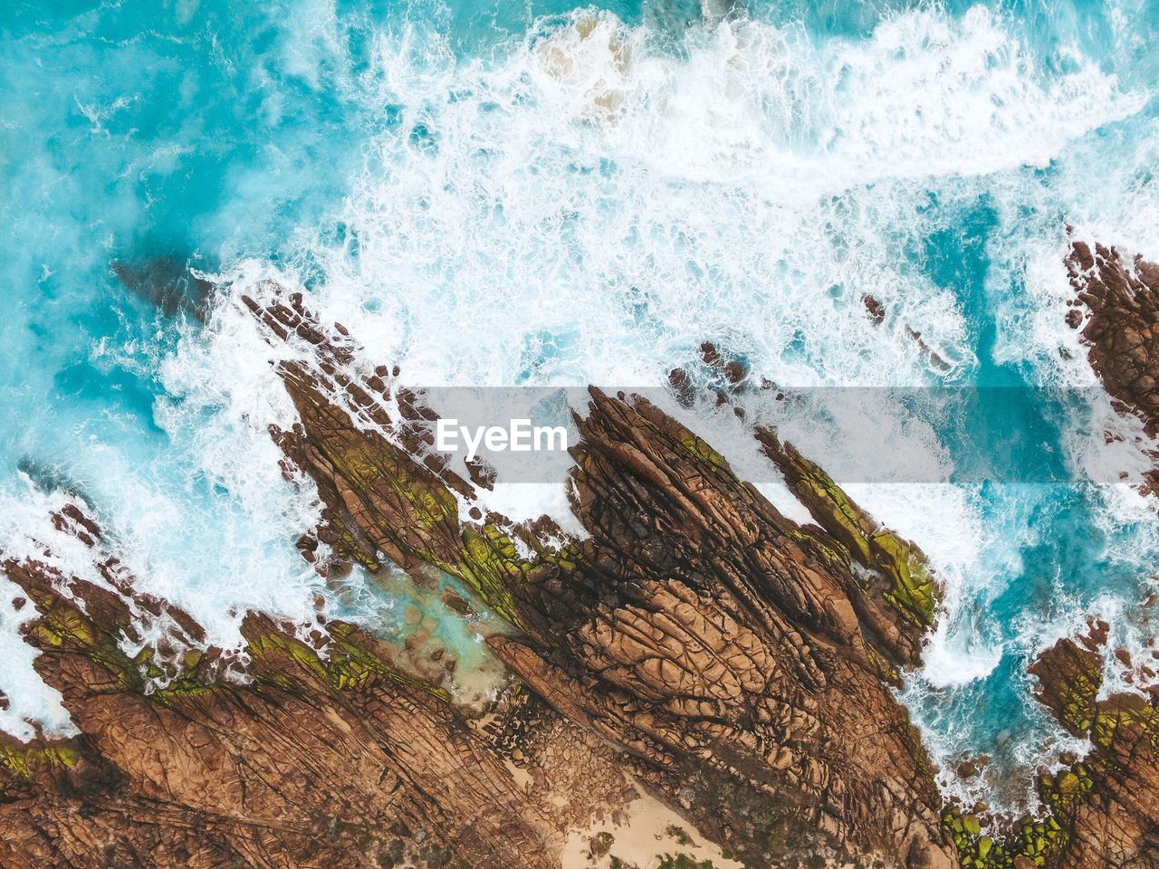 High angle view of sea waves splashing on rocks