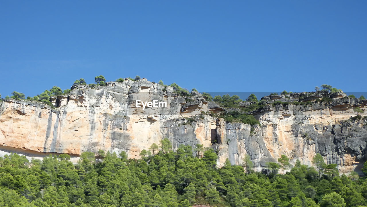 Low angle view of rocks against clear blue sky